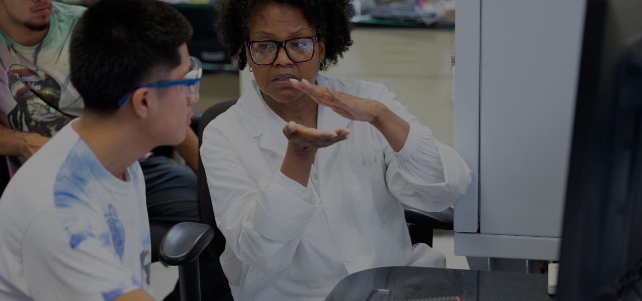 a professor works with a student in a lab