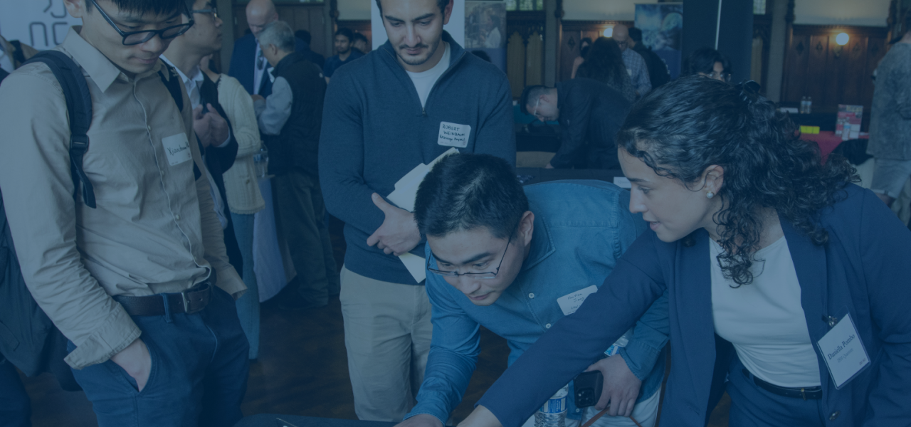 People gathered around a table with a laptop at an event, with an "IBM Quantum" sign.