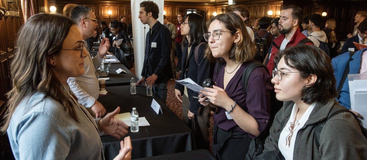 Three women talking over a table at recruiting event
