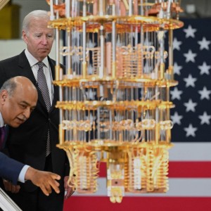 Joe Biden inspecting a gold dilution refrigerator in front of an American flag at IBM in NY