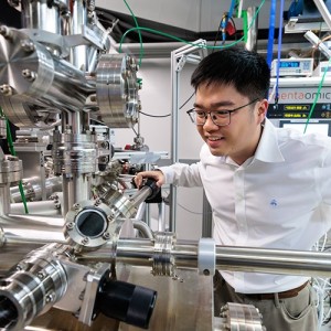 Man examining complex lab machinery with stainless steel components and control panels.