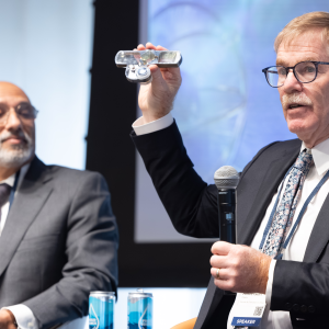 In a panel on Innovating Quantum Sensing, Dana Anderson of Infleqtion displays a component of Infleqtion’s quantum sensor for rotation and acceleration.  