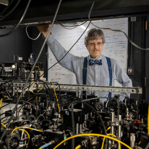 Paul Kwiat standing in his lab, framed by lab equipment.