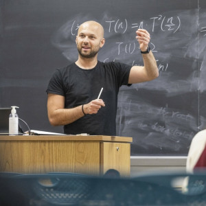 Albarghouthi explaining complex mathematical equations on a chalkboard in a classroom setting.