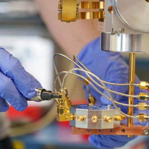Quantum device being manipulated by two hands in nitrile gloves