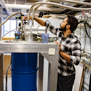 Man stands next to a tall device in a lab