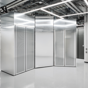 An interior view of a modern data center featuring metallic enclosures labeled "IBM Quantum System Two." The floor is shiny, and the ceiling displays visible pipes and lights.