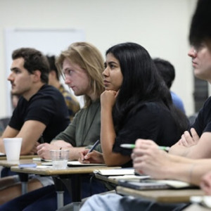 A group of students attentively listening in a classroom setting.