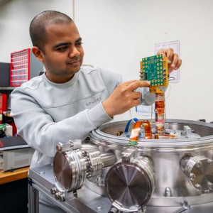 Fermilab engineer Yash Saxena holds a custom circuit board designed to measure chip performance in cryogenic environments. Credit: JJ Starr, Fermilab