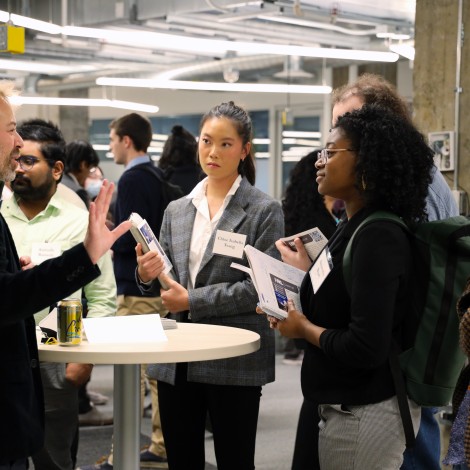 Students at the 2022 Chicago Quantum Recruiting Forum stand around a table listening to a scientist from HRL